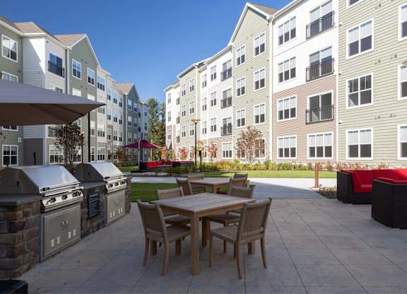 A patio with a table and chairs is surrounded by apartment buildings.