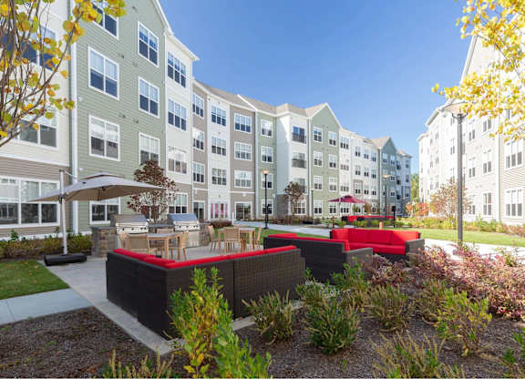 A modern apartment complex with a landscaped courtyard in the foreground.