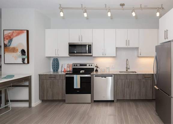 A modern kitchen with a refrigerator, microwave, oven, and sink.