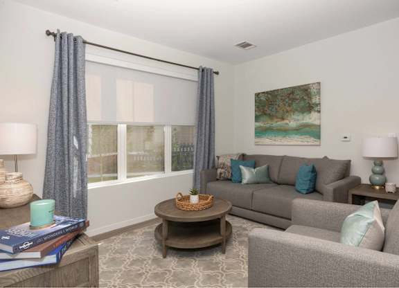 A living room with a grey couch, a coffee table, and a painting on the wall.