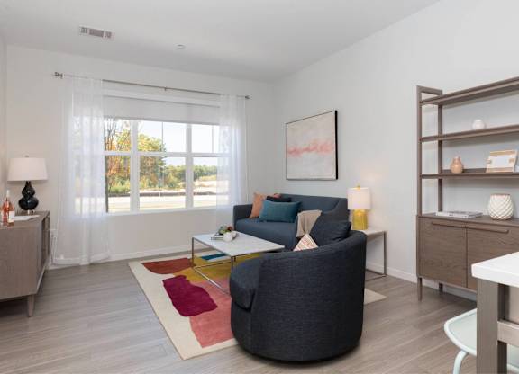 A living room with a grey sofa, a white table, and a wooden cabinet.