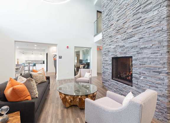 A modern living room with a stone fireplace and a glass coffee table.