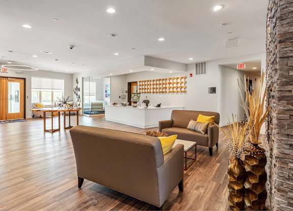 A living room with a brown couch and a stone pillar.