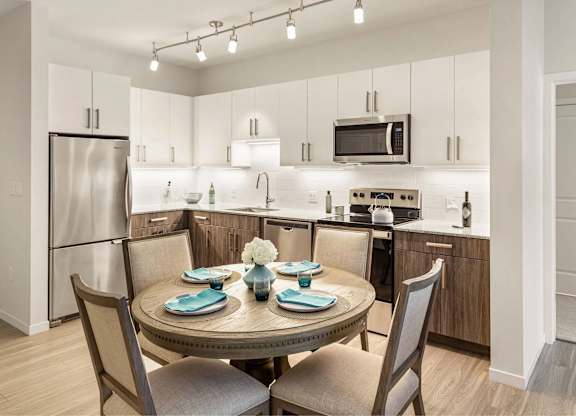 A modern kitchen with a round table set for two.