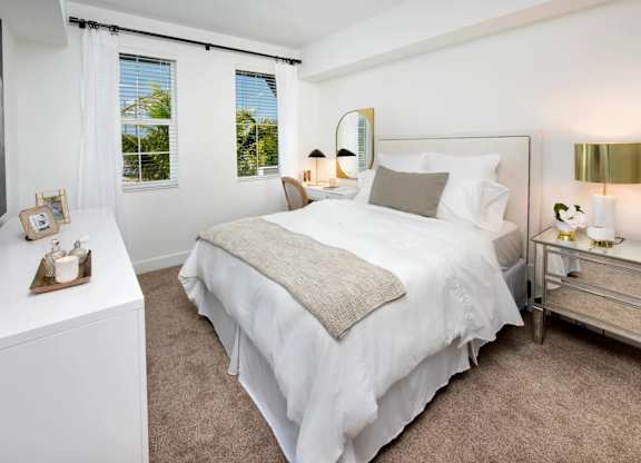 A bedroom with a large bed, a nightstand, and a window with curtains.