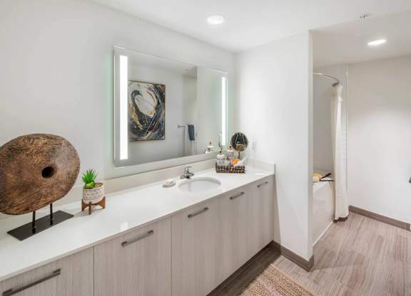 A bathroom with a large mirror, a sink, and a wooden sculpture on the counter.