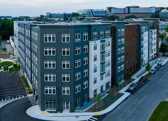 A modern apartment complex with a mix of grey, white, and brown buildings.