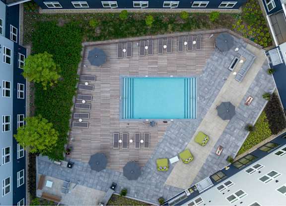 A pool surrounded by a wooden deck and patio furniture.