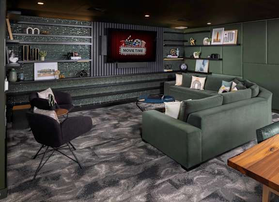 A living room with a grey carpet and a green couch.