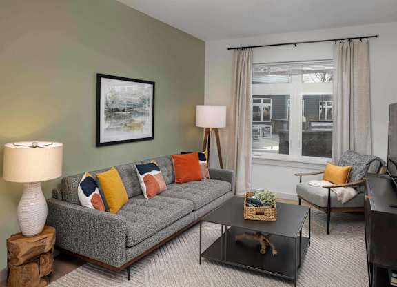 A living room with a grey couch, a coffee table, and a television.