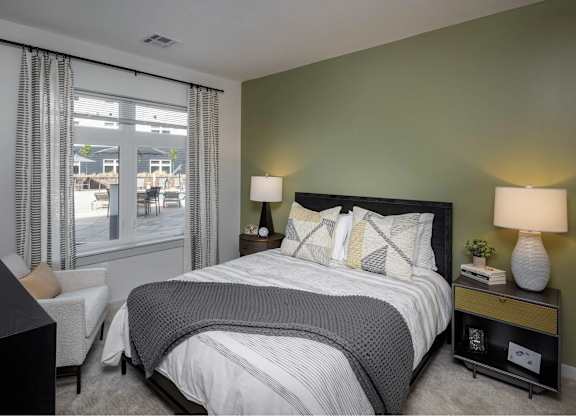 A bedroom with a large bed and a chair by the window.