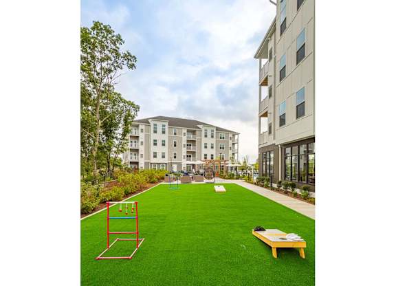 A playground with a swing set and a bench in the middle of a grassy area.