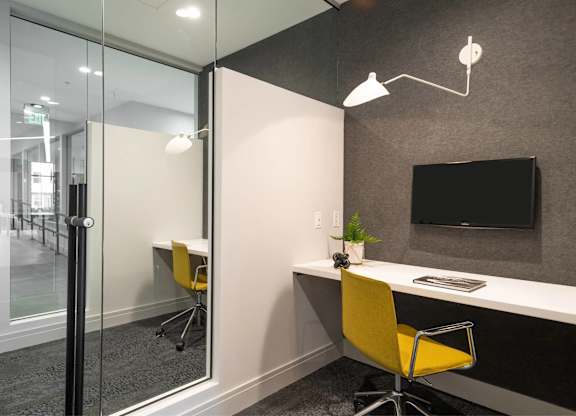 A modern office with a yellow chair and a glass wall.