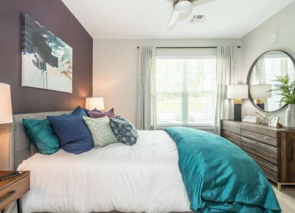 A bedroom with a bed, a ceiling fan, and a mirror.