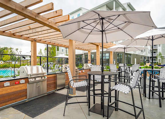 A patio with a grill and chairs under a canopy.