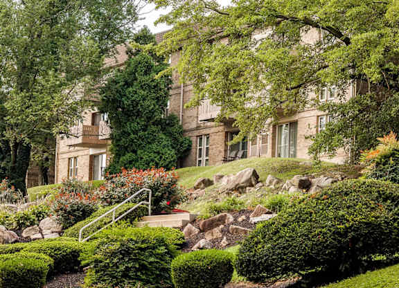 A large house with a green lawn and trees in front.
