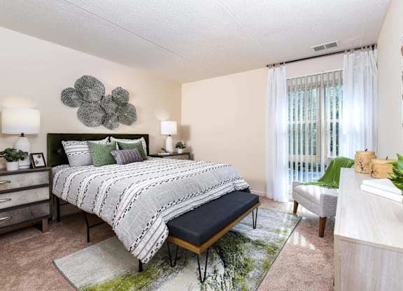 A bedroom with a large bed and a green plant on the side table.