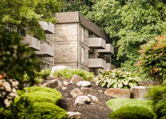 A building with a balcony is surrounded by greenery.