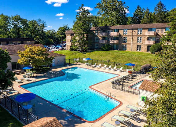 A large swimming pool surrounded by a fence and lounge chairs.