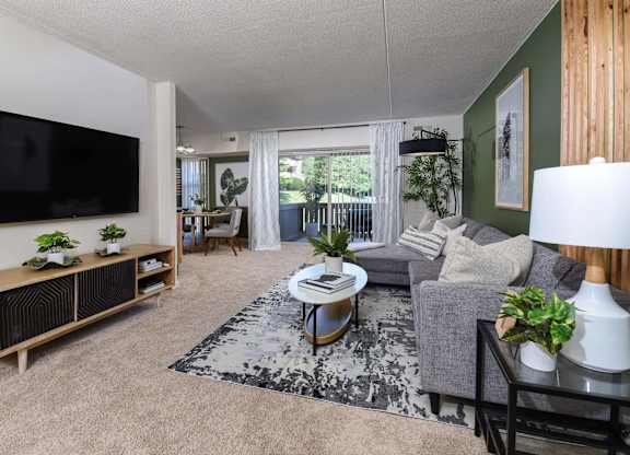 A living room with a grey couch, a black and white rug, and a wooden cabinet.