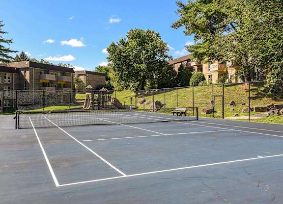 A tennis court surrounded by trees and buildings.