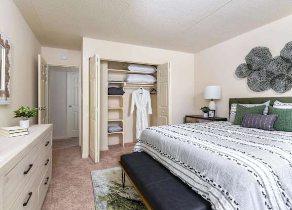 A bedroom with a large bed, a dresser, and a mirror.