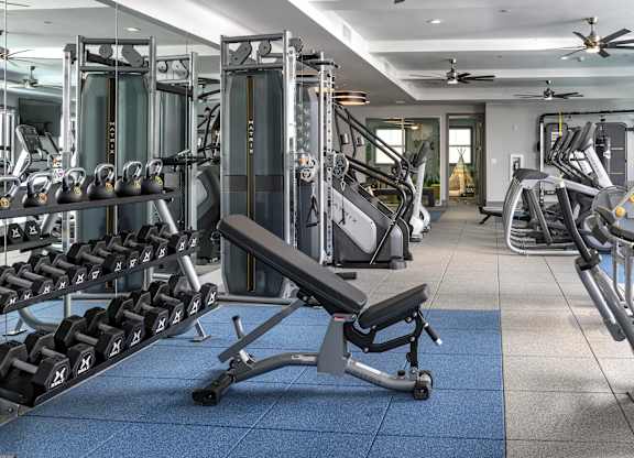 A gym with a variety of equipment including weights and weight machines.