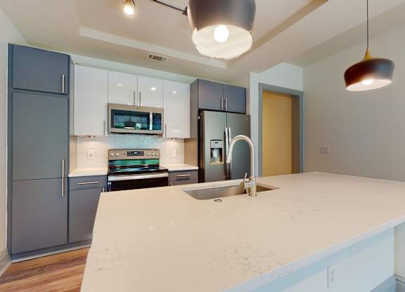 A kitchen with a white counter top and a sink.