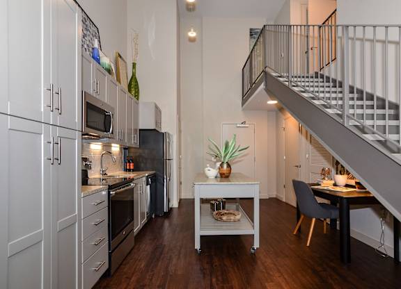 A modern kitchen with a staircase leading to the upper floor.