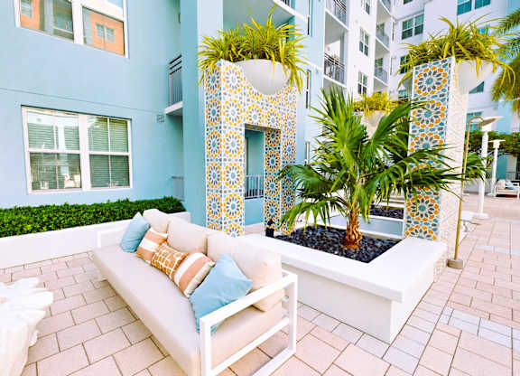 A white couch with blue pillows sits on a patio.