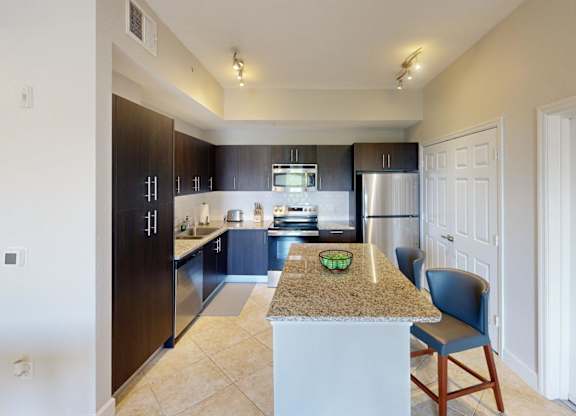 A kitchen with a granite countertop and a blue chair.