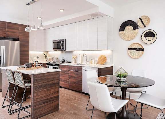 A modern kitchen with a wooden island and white chairs.