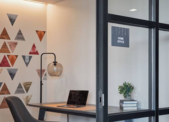 A black chair is in front of a desk with a laptop on it.