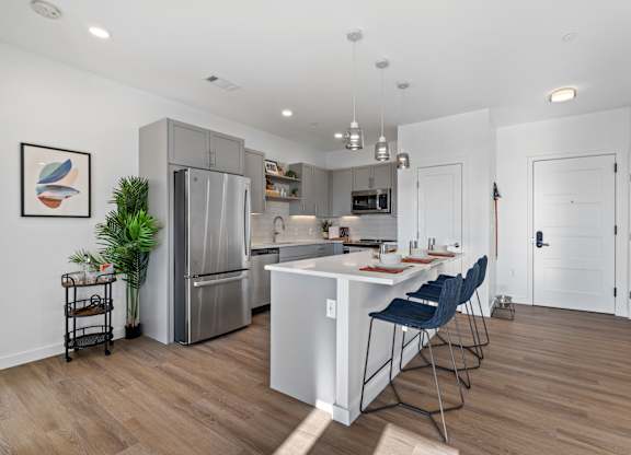 A kitchen with a white island and blue chairs.