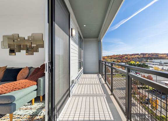 A balcony with a couch and pillows overlooking a city.