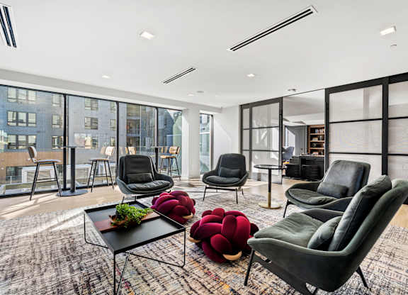A living room with black chairs and a table with a plant on it.
