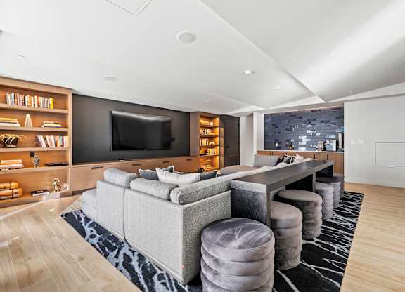A modern living room with a grey sofa and a black television.
