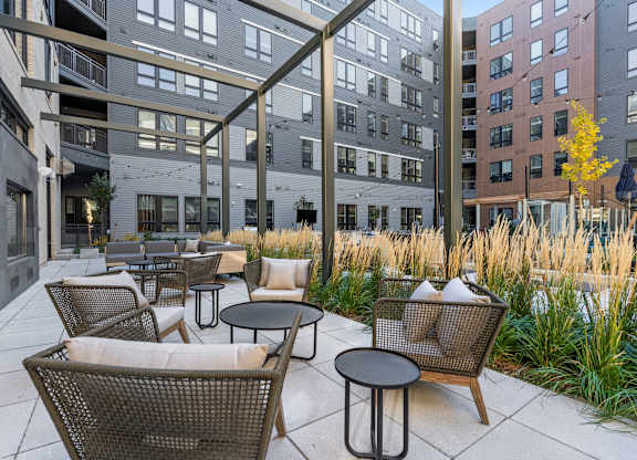 A patio with chairs and tables is surrounded by buildings.