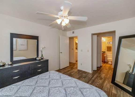 A bedroom with a bed, dresser, mirror, and ceiling fan at Red Mountain Apartments, Mesa, AZ