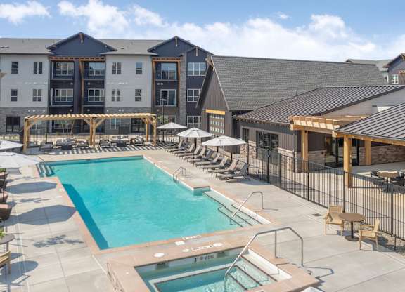 A large outdoor swimming pool surrounded by lounge chairs and umbrellas.