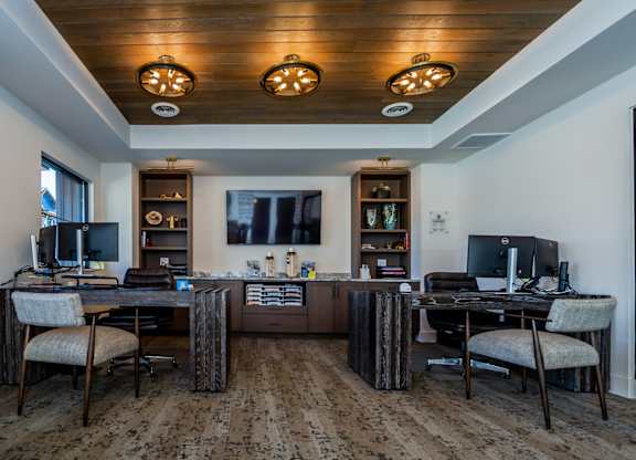 A room with two desks and chairs, one of which is a gaming chair.