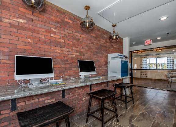 A room with a brick wall and two computer monitors.