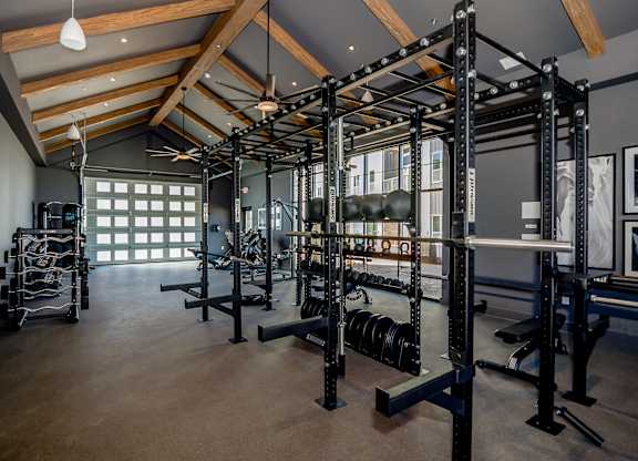 A gym with a variety of equipment including weightlifting machines and dumbbells.