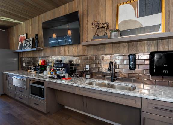 A modern kitchen with a wooden ceiling and a black fridge.