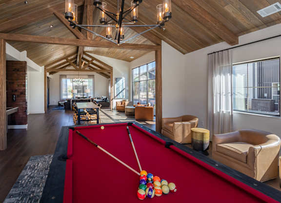 A pool table with a red cloth and a pool cue with a colorful pool ball on it.