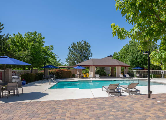a swimming pool with patio furniture and umbrellas