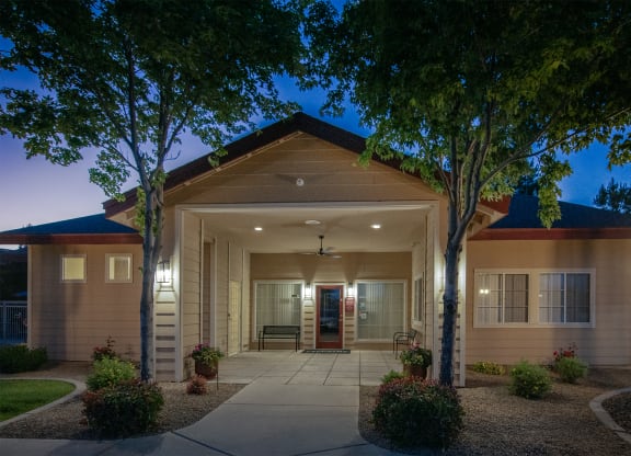 the front of a building at night with trees and a sidewalk