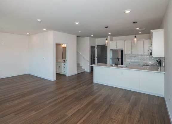 a kitchen and living room with white walls and wood flooring at The Crossings  at Windsong, Arizona