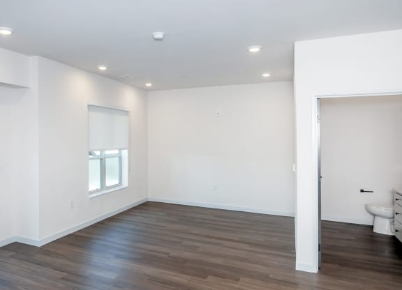 an empty living room with white walls and wood flooring at The Crossings  at Windsong, Arizona