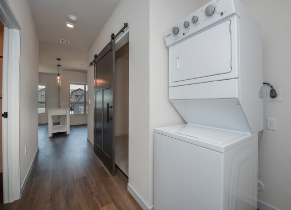 a laundry room with a washer and dryer and a hallway with a door at The Crossings  at Windsong, Prescott Valley, Arizona